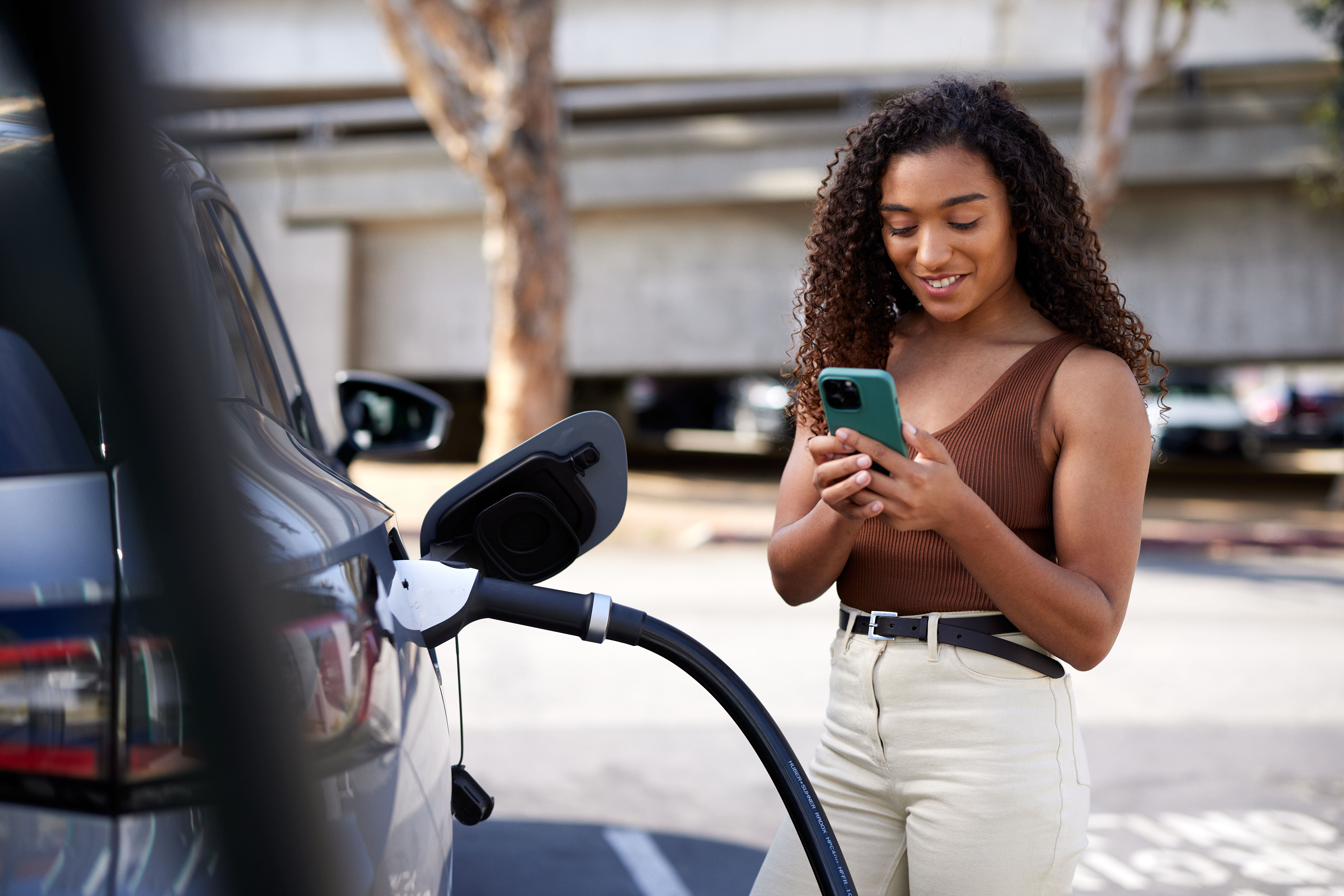Woman charging her EV and looking at her phone